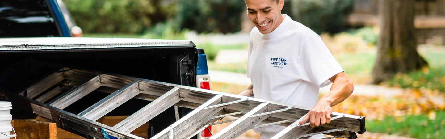 Five Star Painting employee loading ladder into back of a truck