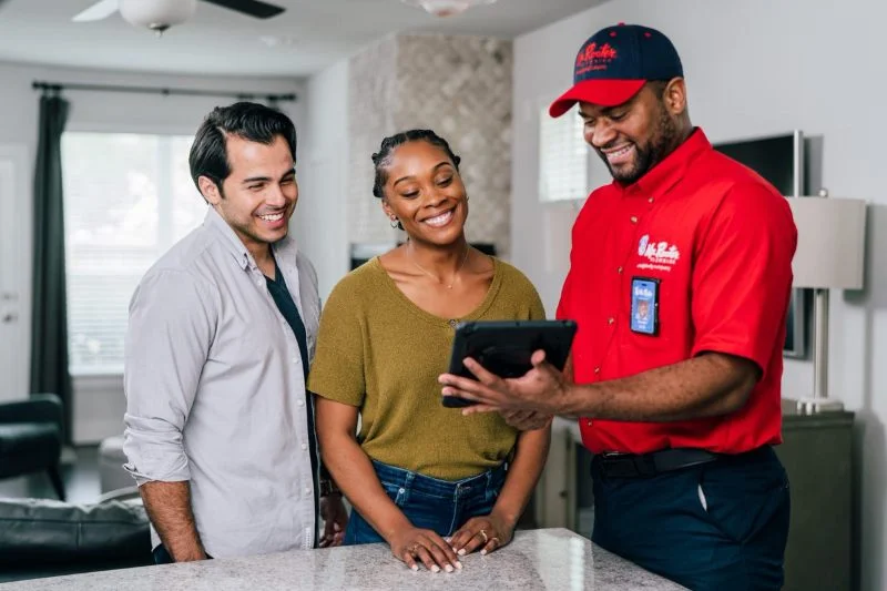 A Mr. Rooter plumber showing customers options for water heater repair.