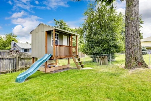 Playhouse with slide in the backyard of a residential home.