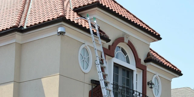 ladder against top floor of Spanish style home