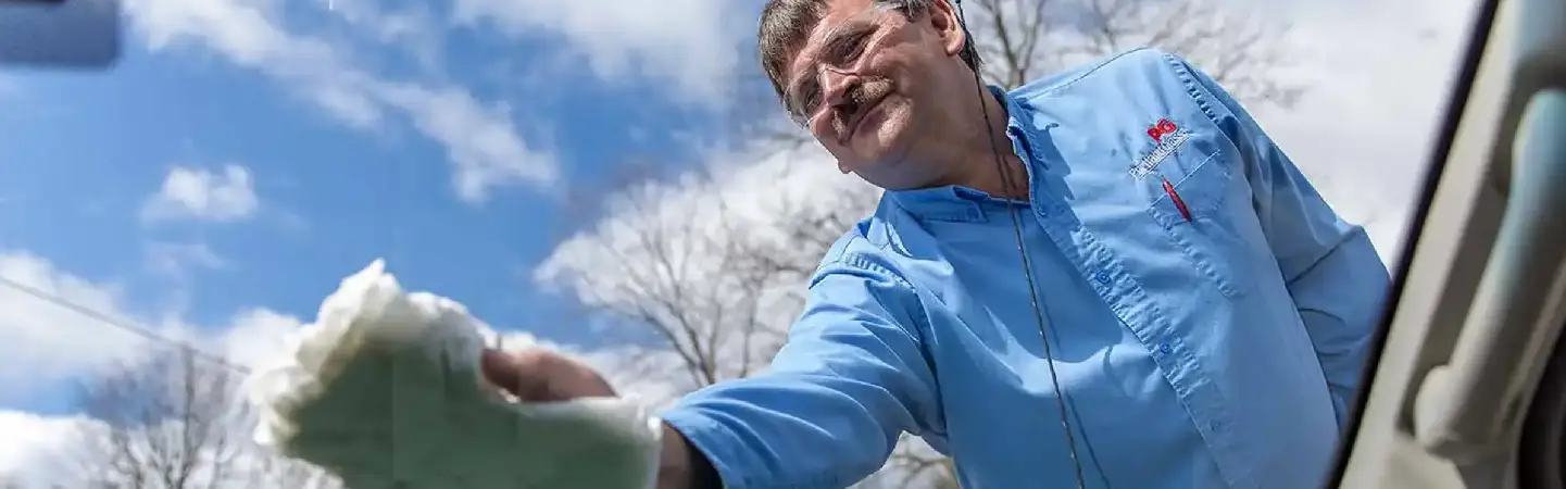 Man washing a car windshield with a cloth.