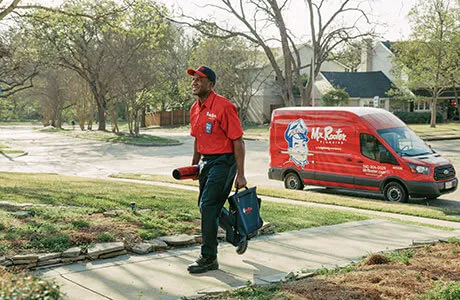 a Mr. Rooter plumber walking up to a house.