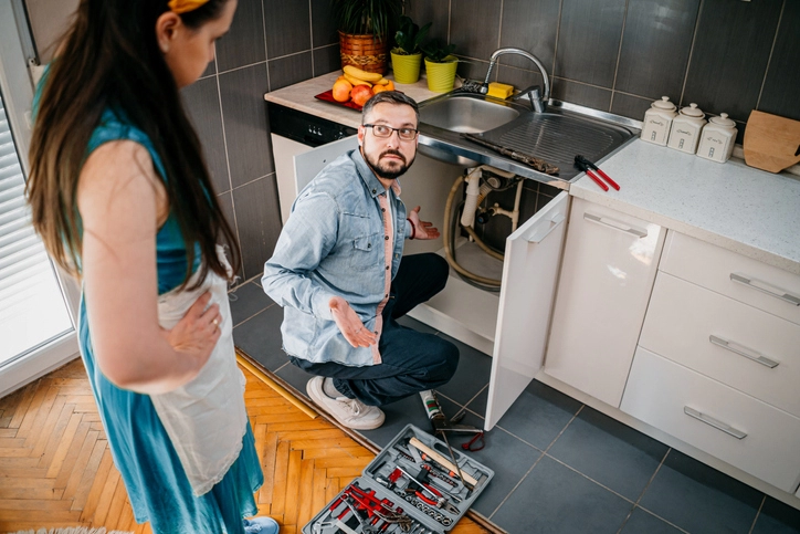 Man shrugging while fixing plumbing and woman standing behind him | Mr. Rooter Plumbing of Memphis