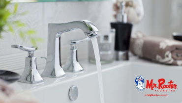 A strong stream of water coming out of a stainless steel faucet on a white bathroom sink.