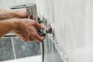 Hands turning bathroom faucet