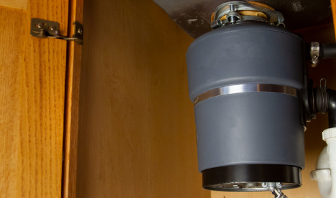 A gray garbage disposal installed under a sink.