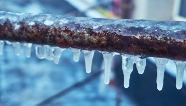 Small icicles hanging from a frozen rusty pipe