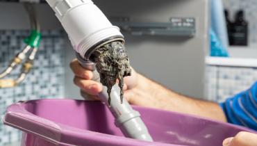 A plumber removes blockage from residential pipes.