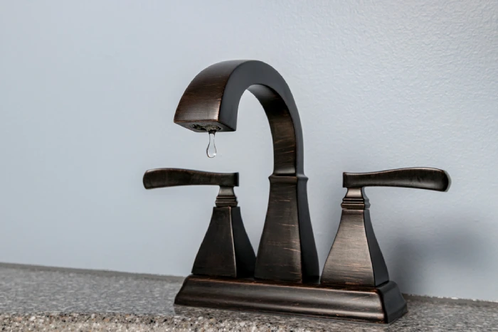 Bathroom sink faucet with water dripping.