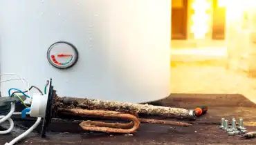 A corroded heating element sitting on the outside of a water heater.