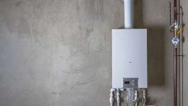 Image of a new water heater on the concrete wall of a garage.