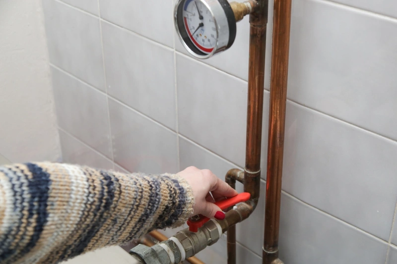 Homeowner adjusting central heating valve to keep warm during the colder months. | Mr. Rooter Plumbing of South Jersey.