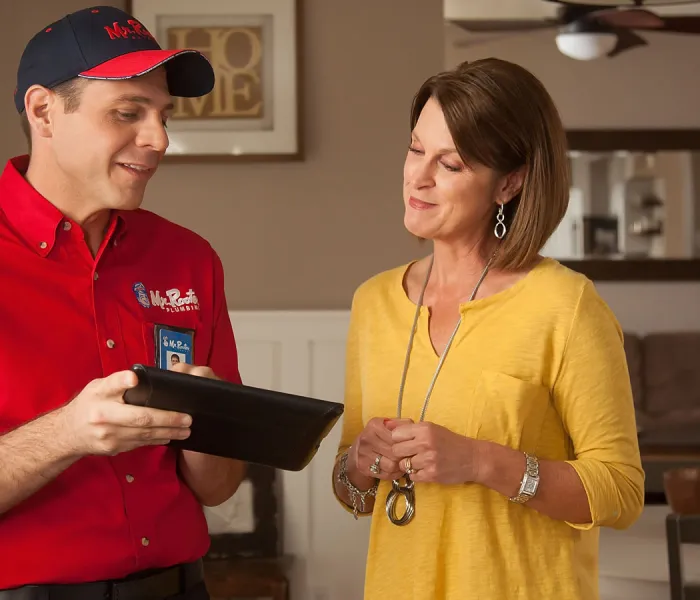 Mr. Rooter technician showing a customer something on an iPad screen.