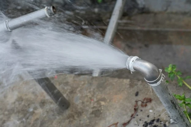 Broken outdoor pipe spraying water into the yard.