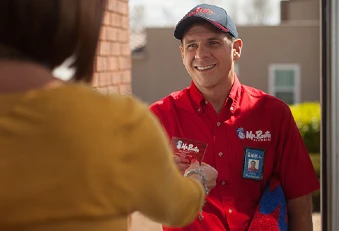 Mr. Rooter professional and experienced plumber smiling and handing homeowner his business card.