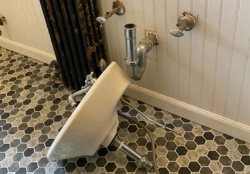 A sink lying on the ground in a residential bathroom before being installed by a plumber in East Hampton, NY.