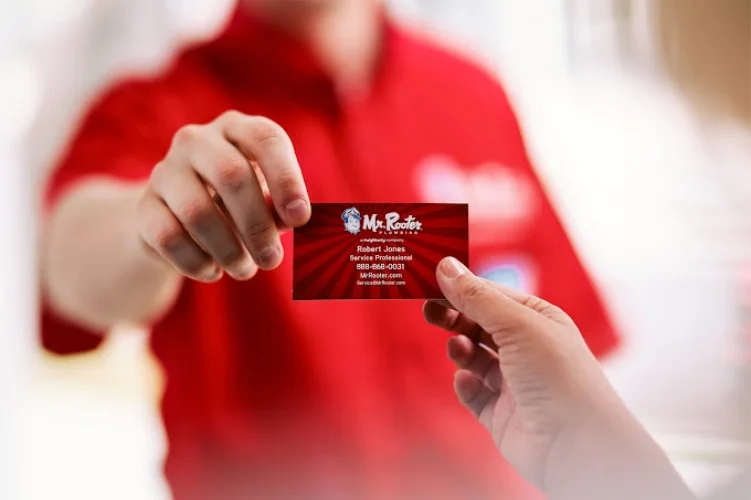 Mr. Rooter plumber showing a business card.