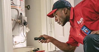 Mr. Rooter employee checking a water heater with a flash light.