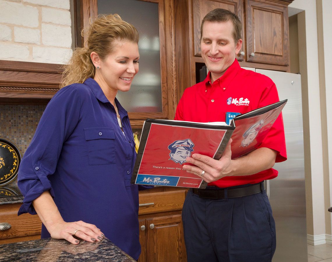 Mr. Rooter technician and customer browsing through a brochure.