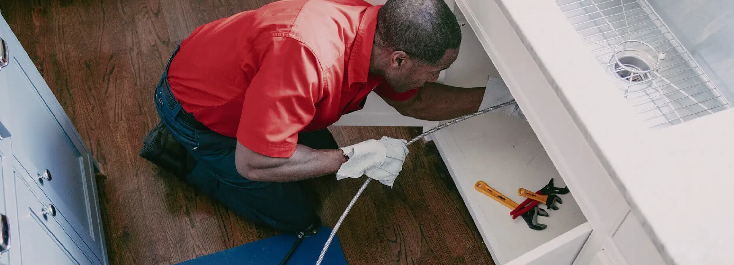 Mr. Rooter employee using a snake to unclog a sink.