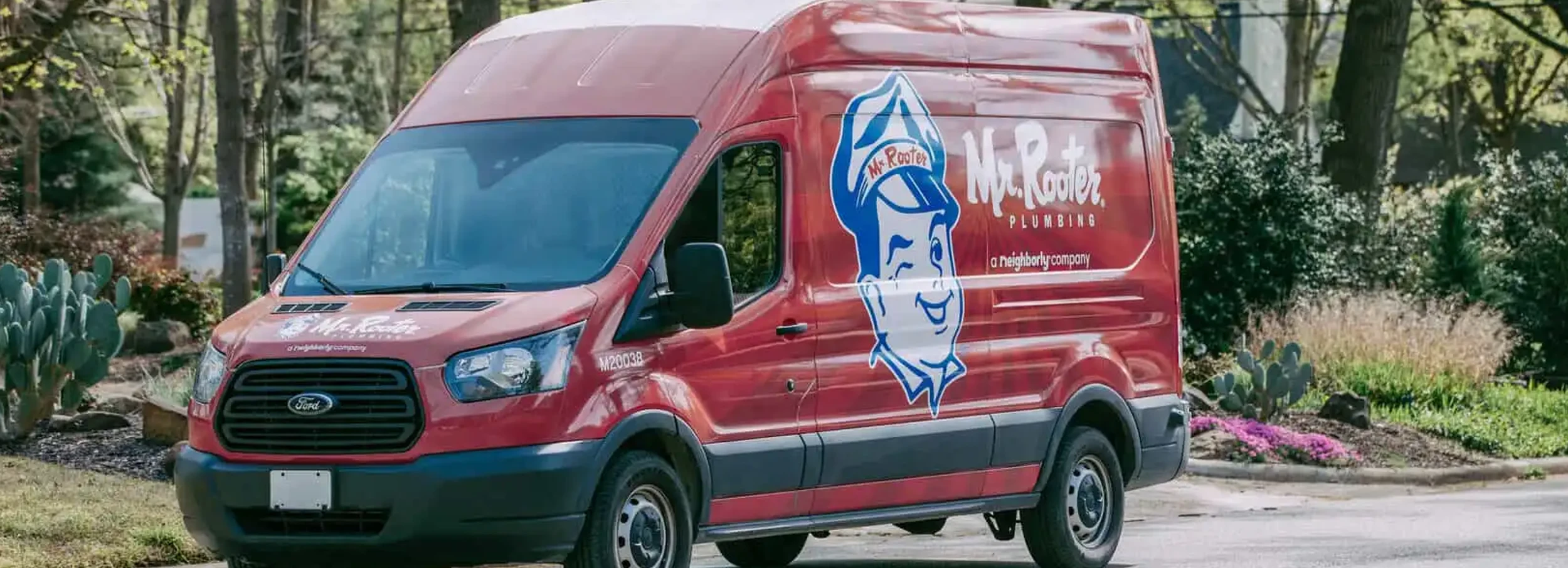 Mr. Rooter branded van parked in front of large gray residential home.