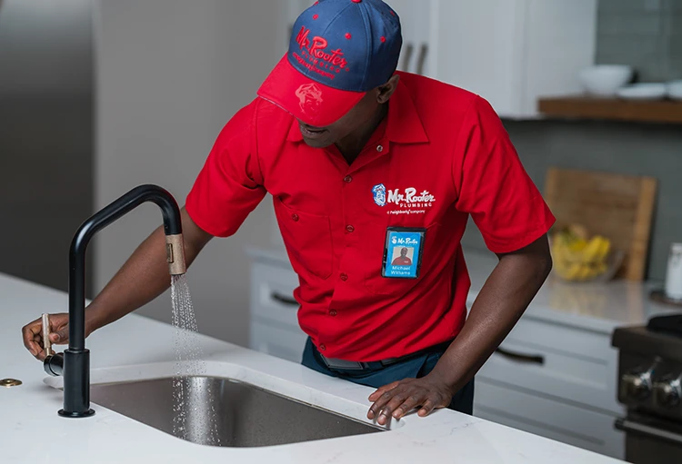 Mr. Rooter plumber working under a kitchen sink during a sink repair appointment.