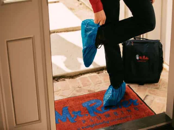 Mr. Rooter employee putting on shoe covers before entering customer's home.