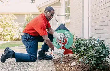 Mr. Rooter plumber outside a client's home fixing a drain.