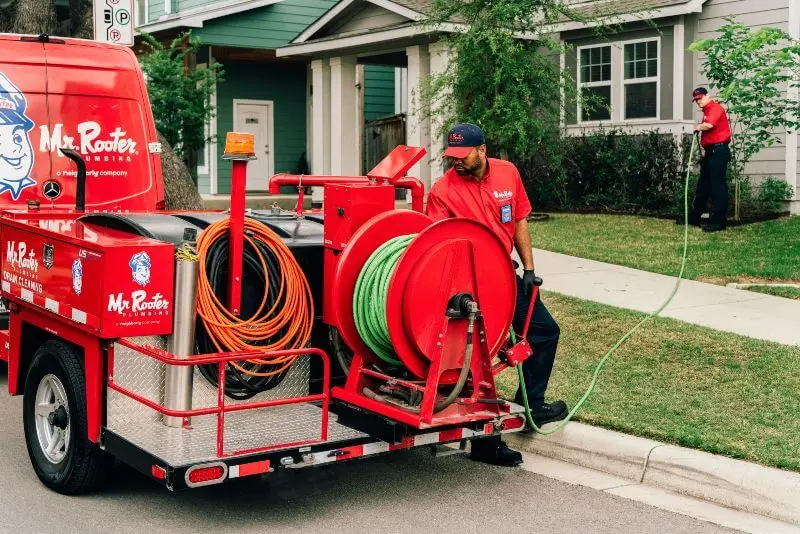 Mr. Rooter plumbers performing a hydroscrub jetting service outside a house