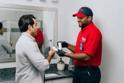 A Mr. Rooter Plumbing technician showing a bathroom sink p-trap to his customer