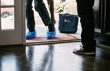 MRR technician putting booties on before entering home