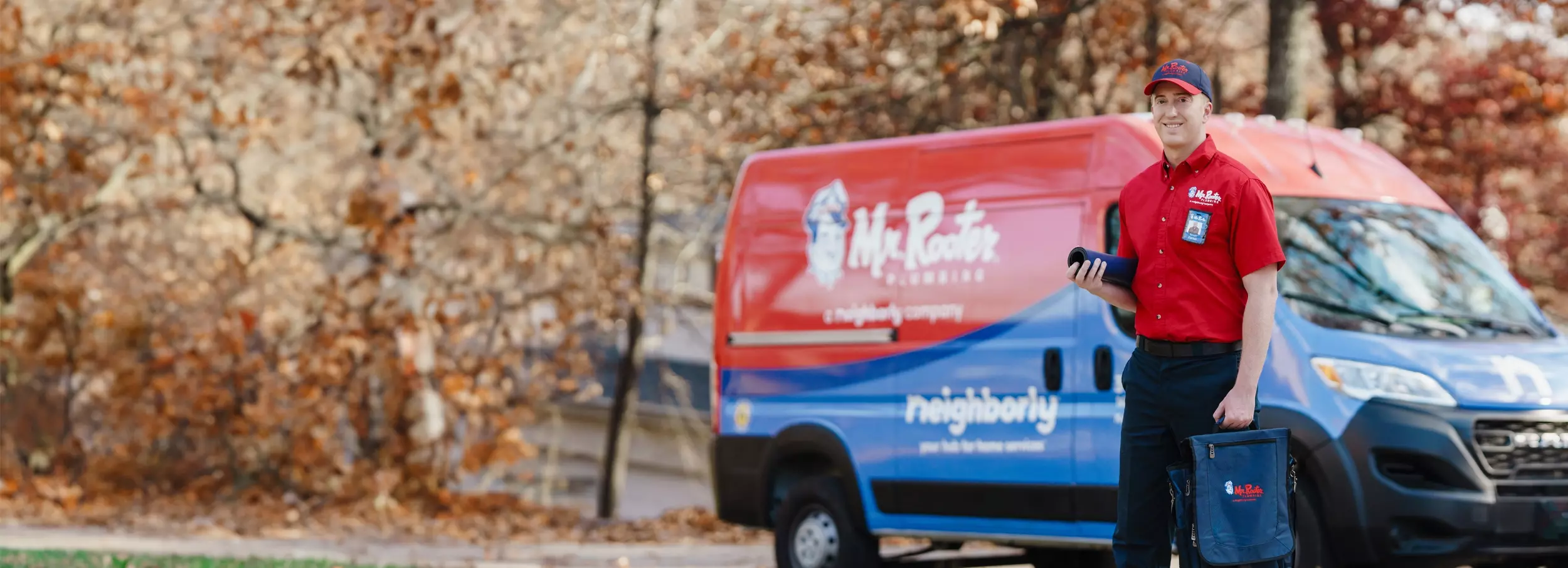 Mr. Rooter technician standing beside a branded van.