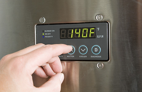 Fingers pressing a button on a tankless water heater in clearwater, FL