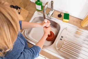 Woman plunging sink in need of drain cleaning in Macon, GA