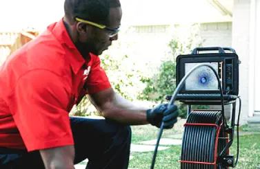 A Mr. Rooter Plumbing service professional using a plumbing camera to inspect a sewer line