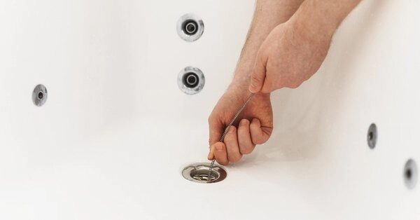 A Mr. Rooter Plumbing technician using a drain snake to deal with a clogged drain in Fort Worth, TX