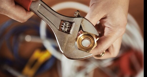 A plumber using a wrench to fix a pipe during an appointment for plumbing repair in Fort Worth, TX.