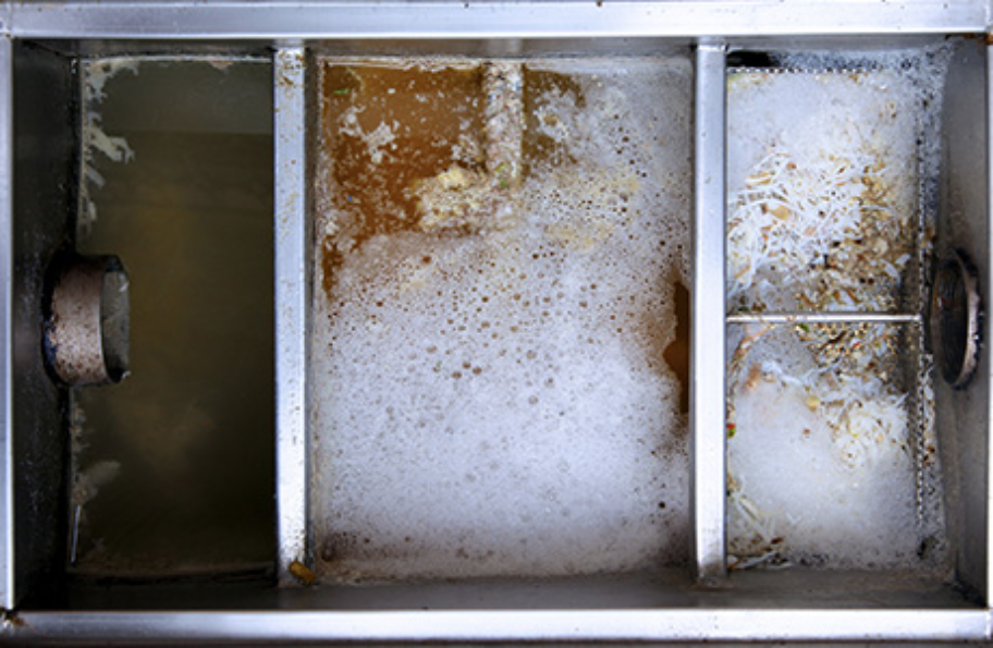 A grease trap being cleaned with soapy water.