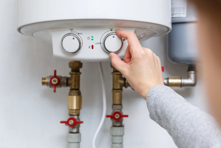 A person adjusts a knob on their hot water heater. | Mr. Rooter Plumbing of Yavapai, Coconino and Maricopa Counties