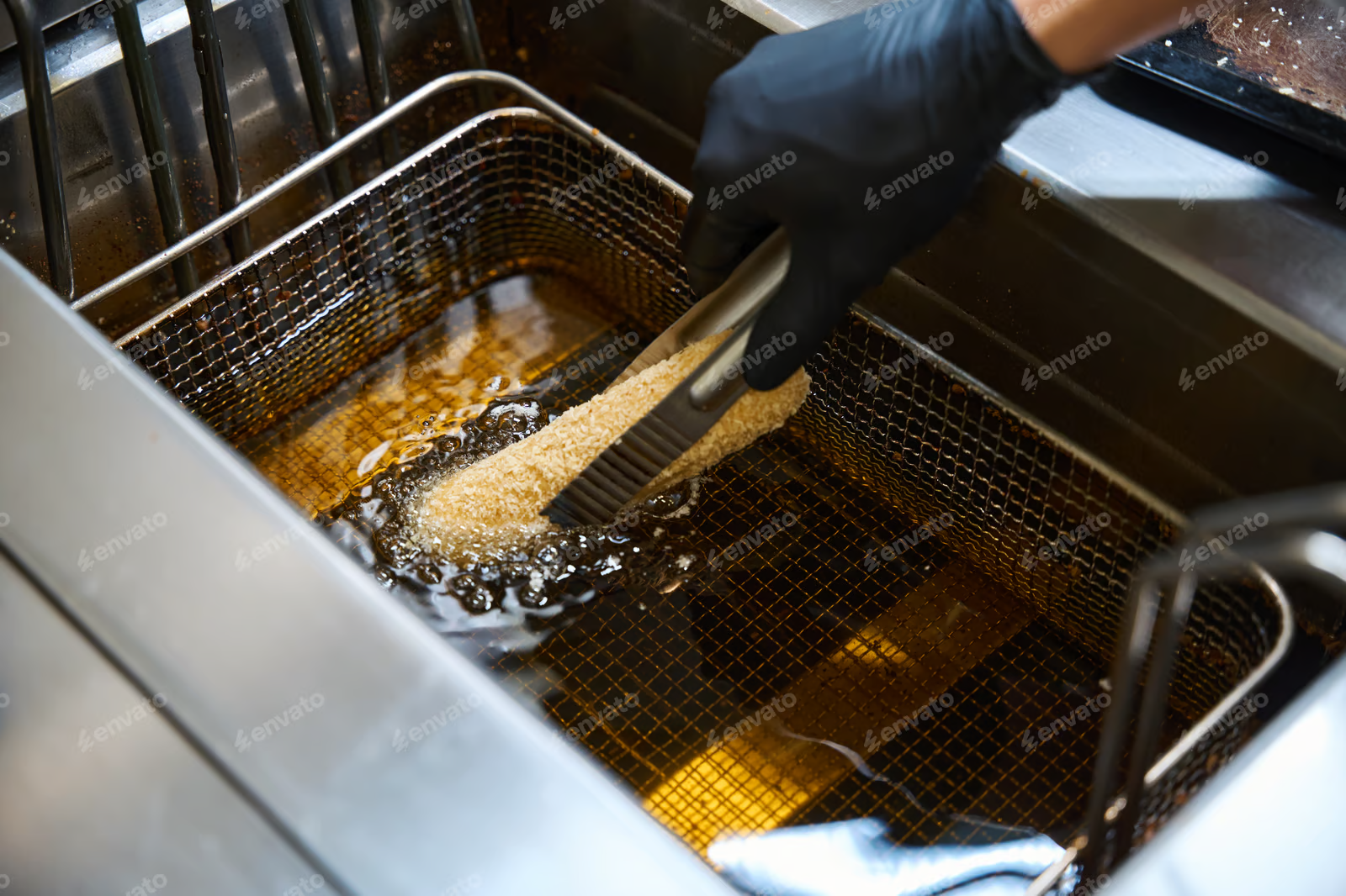 Kitchen worker deep-fries food in oil destined for commercial grease trap