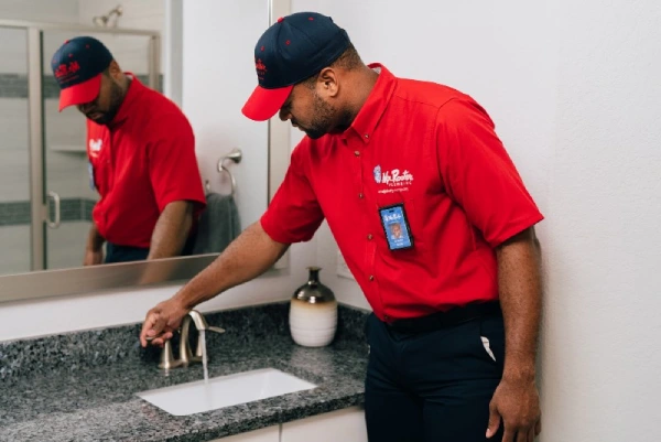 Mr. Rooter plumber runs water in the sink after drain cleaning.