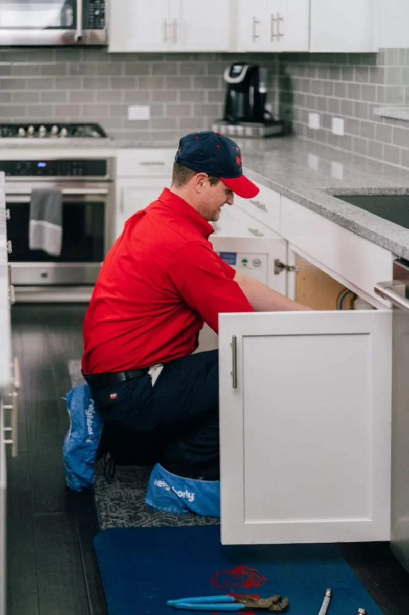 Mr. Rooter plumber completing a garbage disposal repair in a home kitchen 