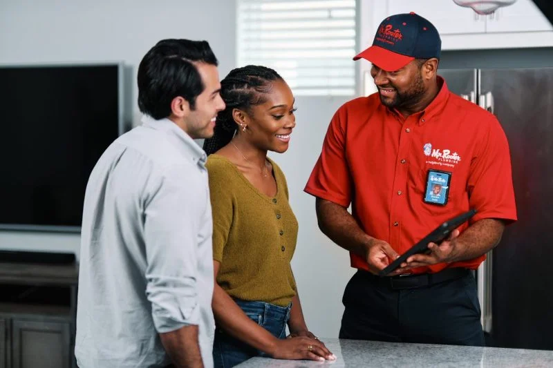 Mr. Rooter plumber discussing plumbing maintenance with a couple.