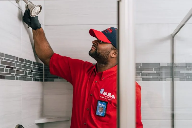 Mr. Rooter plumber installing shower head