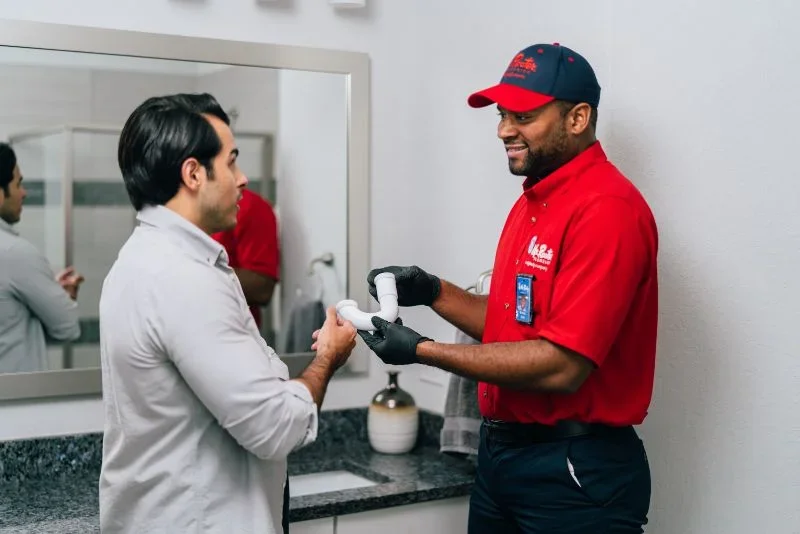 Mr. Rooter plumber showing a drain pipe in homeowner's bathroom