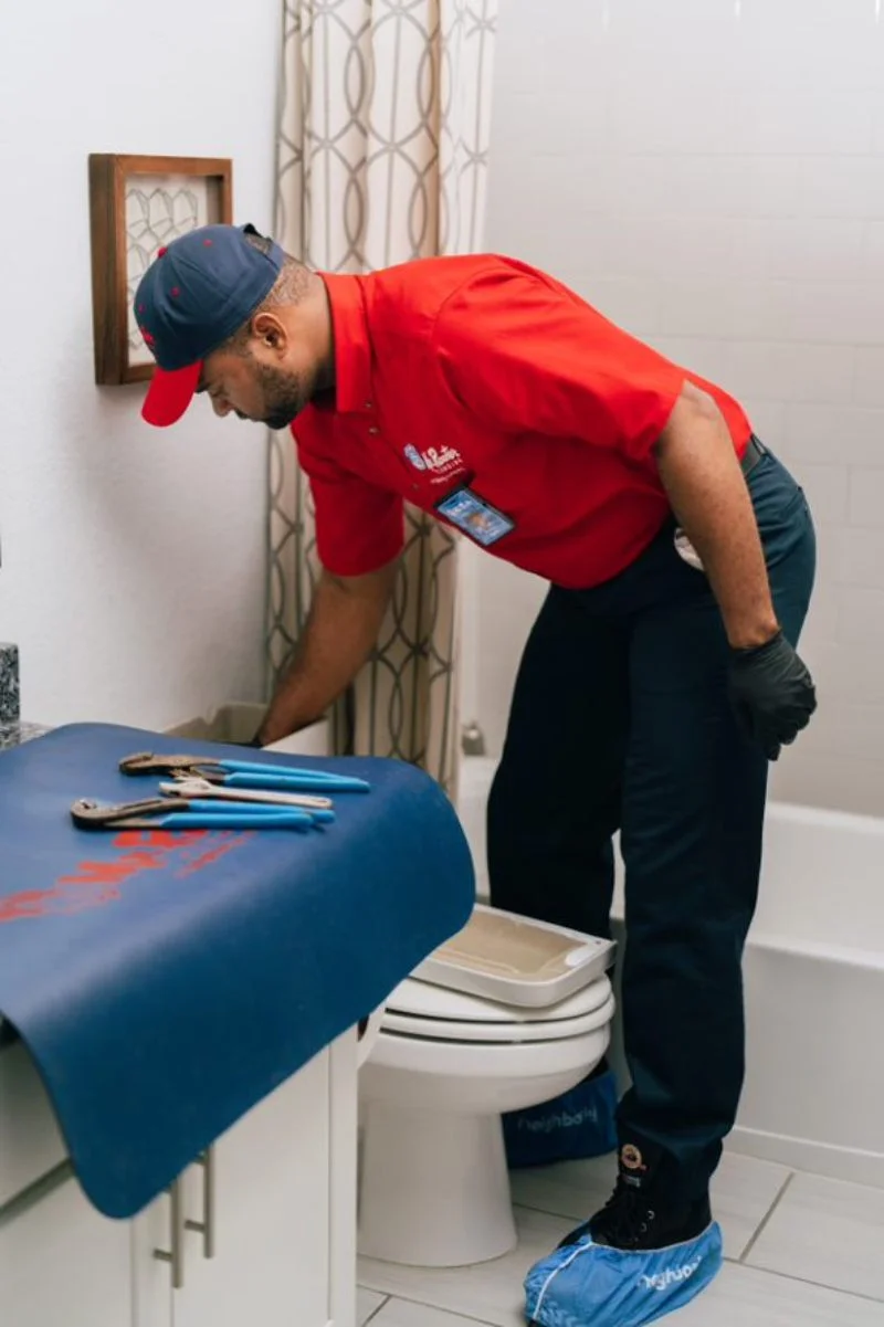 Mr. Rooter plumber inspecting a toilet tank as part of a plumbing inspection 