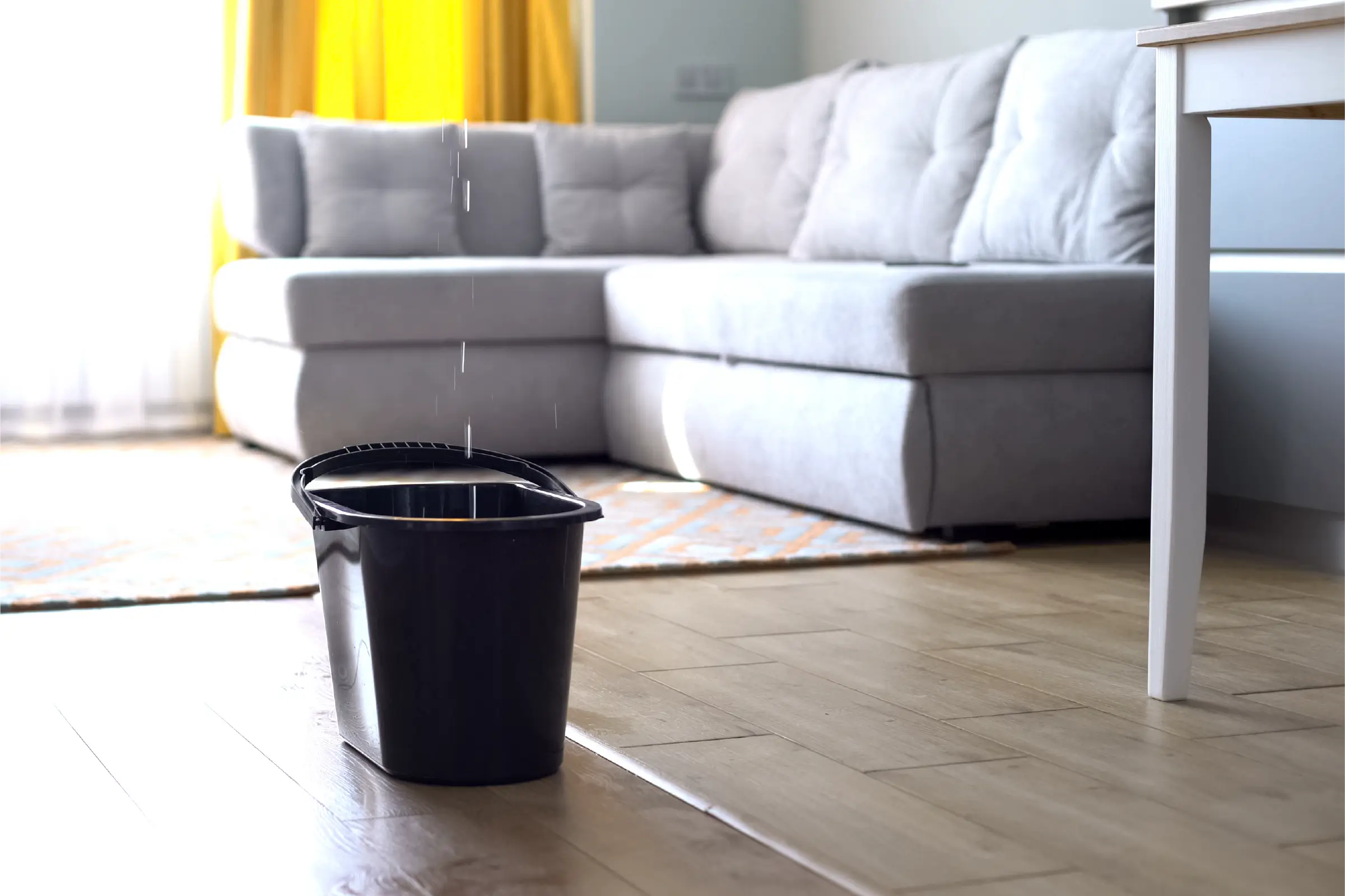 A bucket catches a stream of water leaking from the ceiling