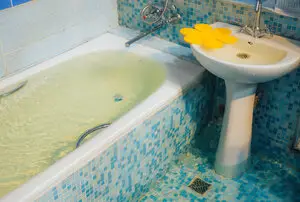 Clogged tub in blue-tiled bathroom in need of clearwater drain cleaning service