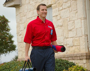 Mr. Rooter plumber carrying plumbing supplies to a home.