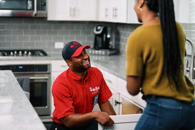 A uniformed Mr. Rooter Plumbing tech about to inspect a kitchen sink drain